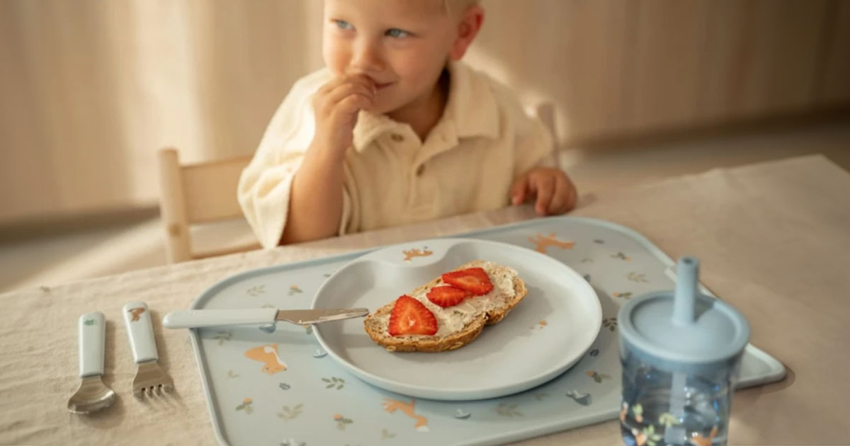 Dieťa sediace za stolom ktoré obeduje tanier, tácky