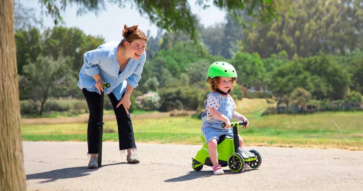 Dieťa pri jazde na pohybovej hračke v prírode pod dohľadom rodiča, ktorá podporuje rovnováhu, istotu v pohybe a radosť z aktívnej hry