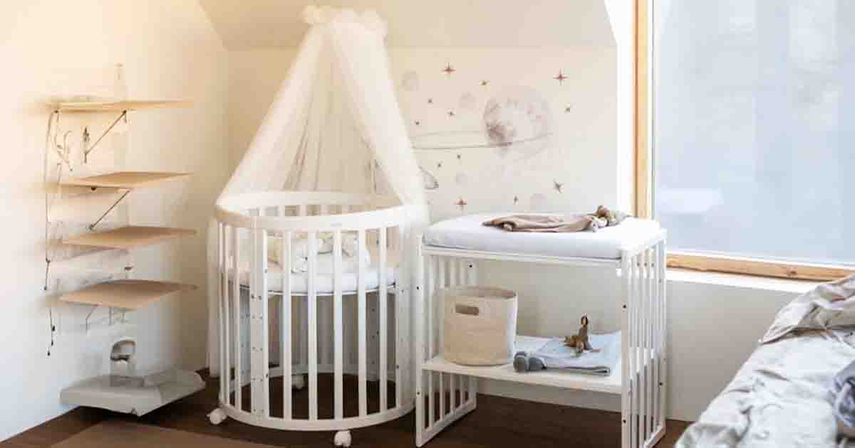 Rastúca detská postieľka s baldachýnom a prebaľovacím pultom v jemne zariadenej detskej izbe, biela okrúhla postieľka v modernom štýle