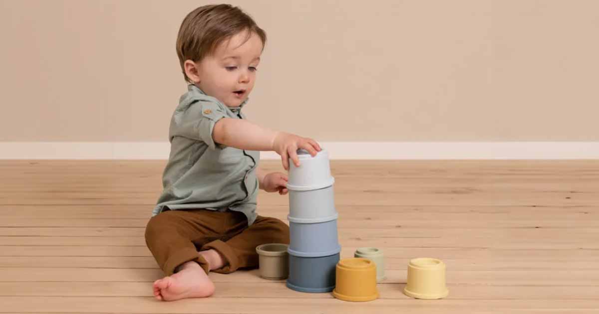 Bábätko pri sústredenej hre so stohovacími pohárikmi, ktoré podporujú jemnú motoriku, koordináciu a objavovanie veľkostí